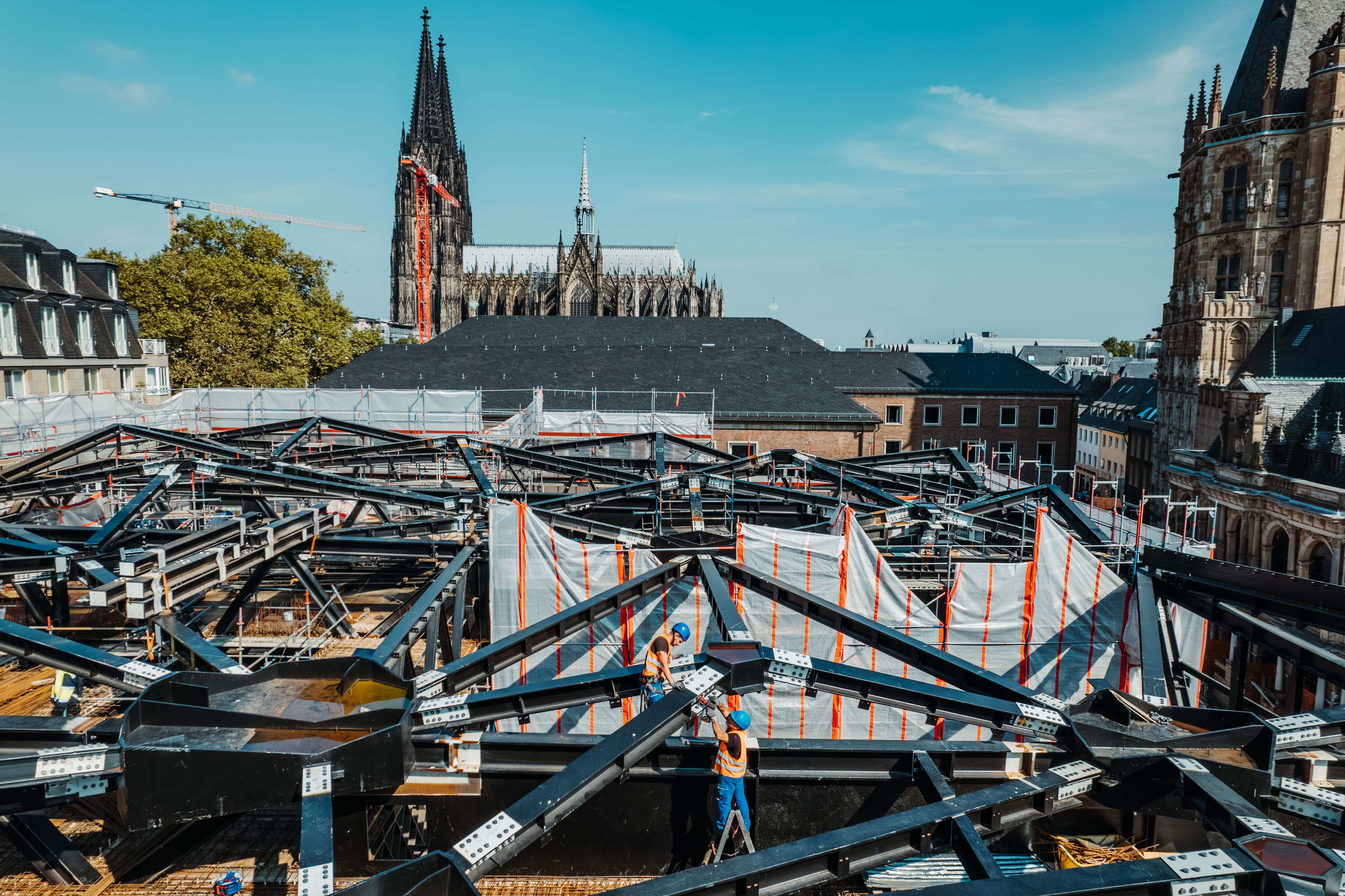 Zwei Arbeiter zwischen den Stahlstreben an einer der Dachpyramiden vor dem Kölner Dom.