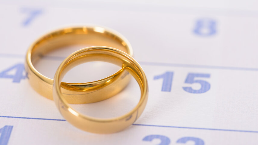 Zwei goldene Trauringe liegen auf einem Kalenderblatt