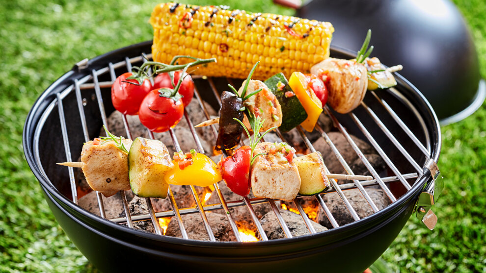 Grill mit Gemüse und Spieß auf einer Wiese