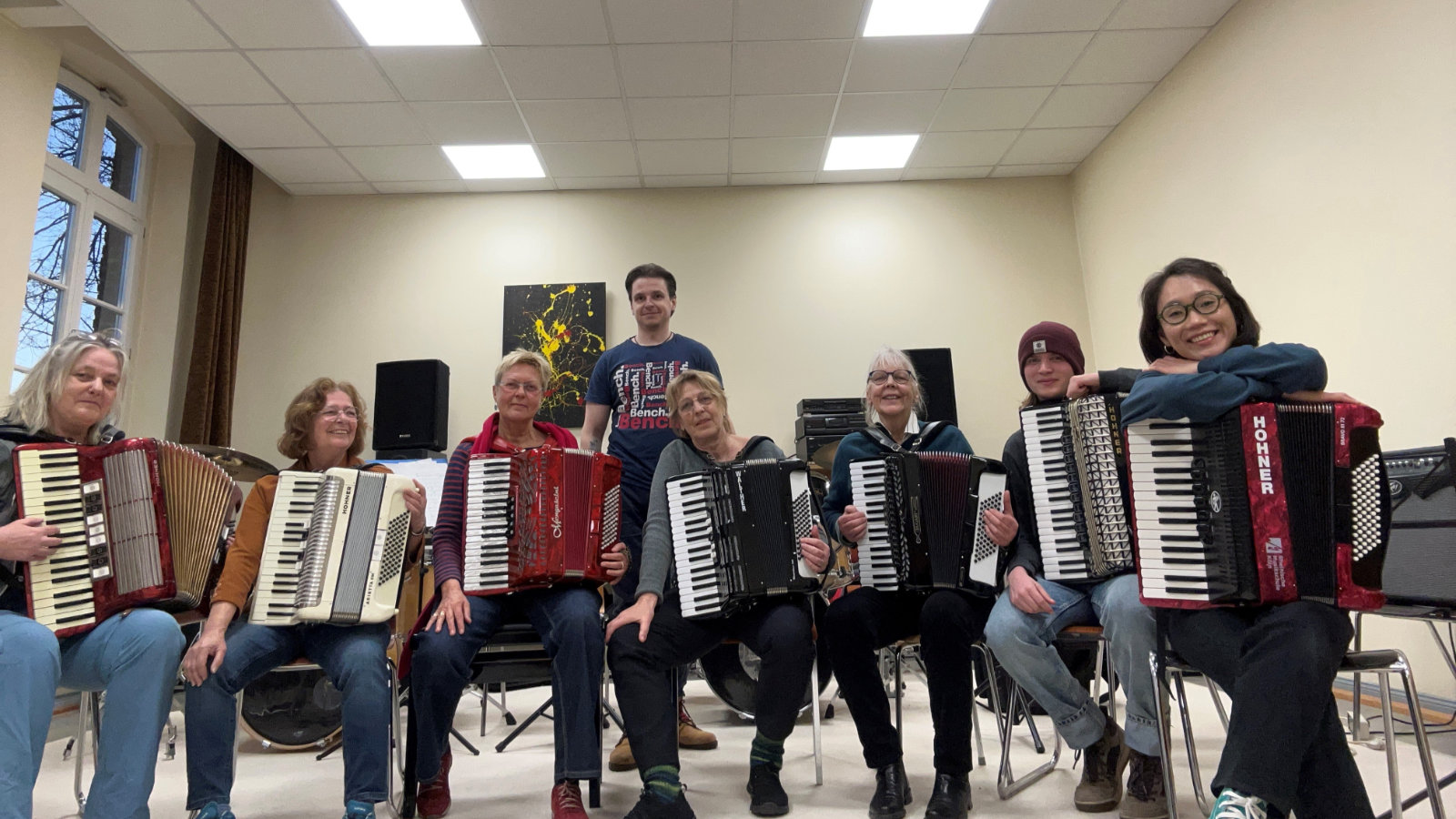 7 Akkordeonistinnen mit ihren Akkordeons in ihrem Probenraum, im Hintergrund der Leiter Vadim Baev