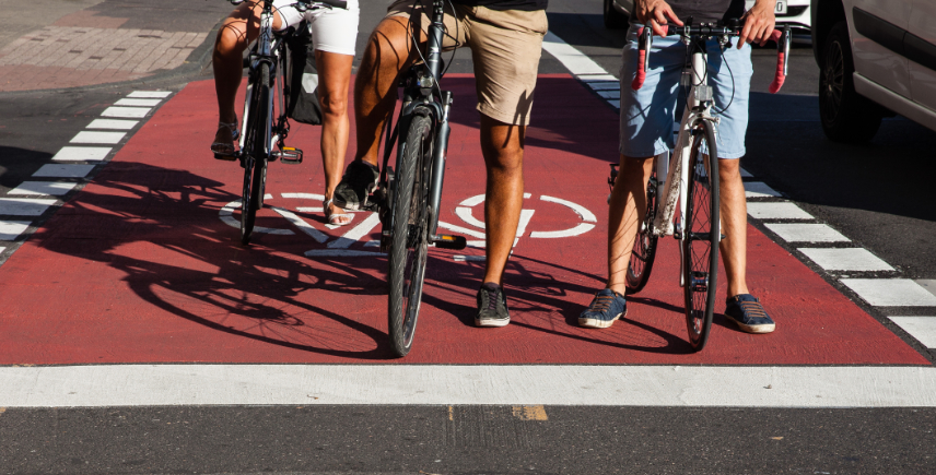 mehrere Radfahrende stehen auf einem rot markierten Radfahrstreifen