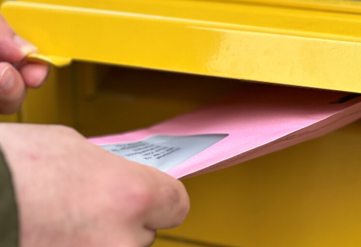 Person wirft roten Wahlbrief in einen Briefkasten, © Stadt Köln